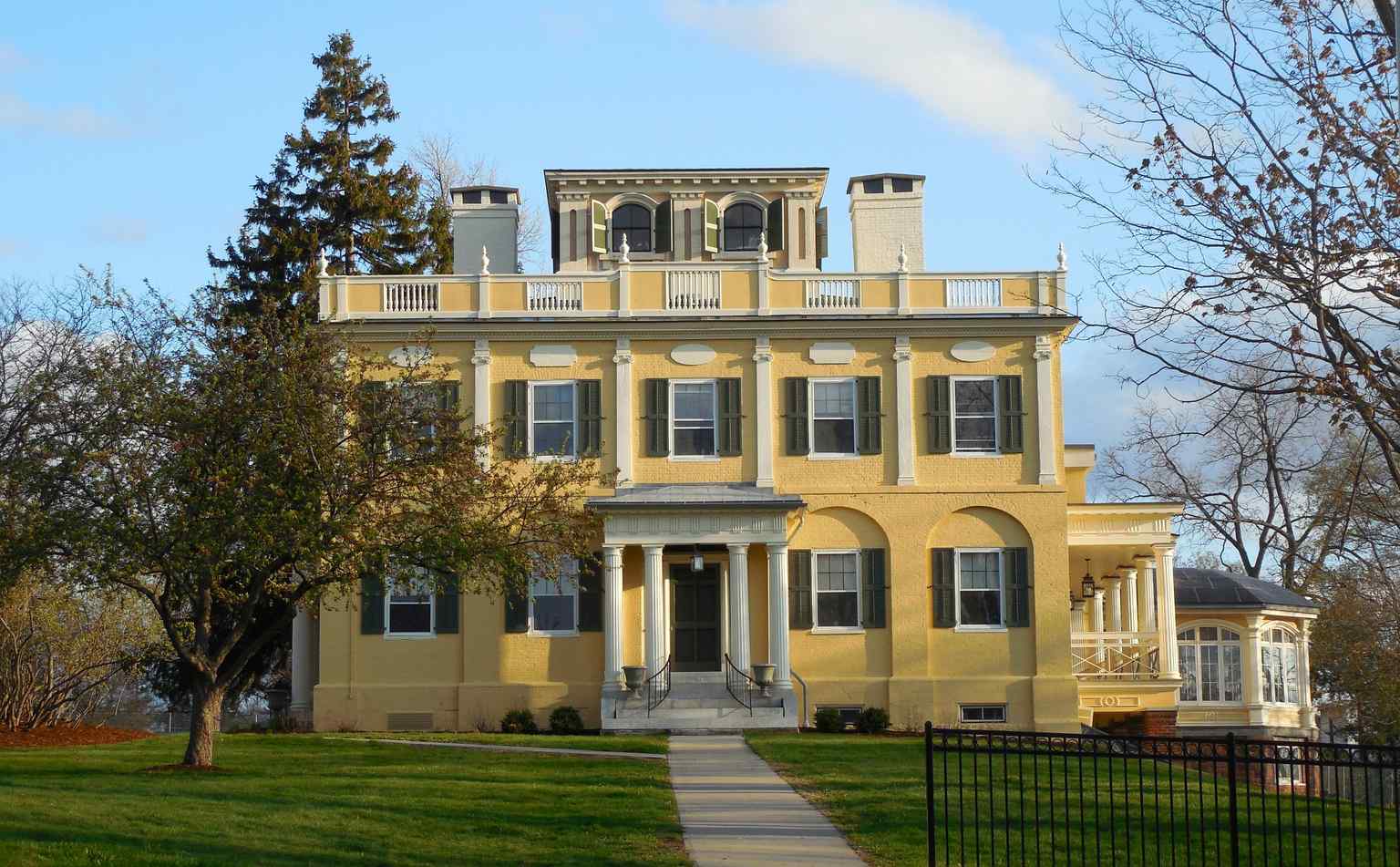 This sophisticated example of Federal domestic architecture features Ionic pilasters, a Doric portico, and a prominent fanlight above the main entrance.