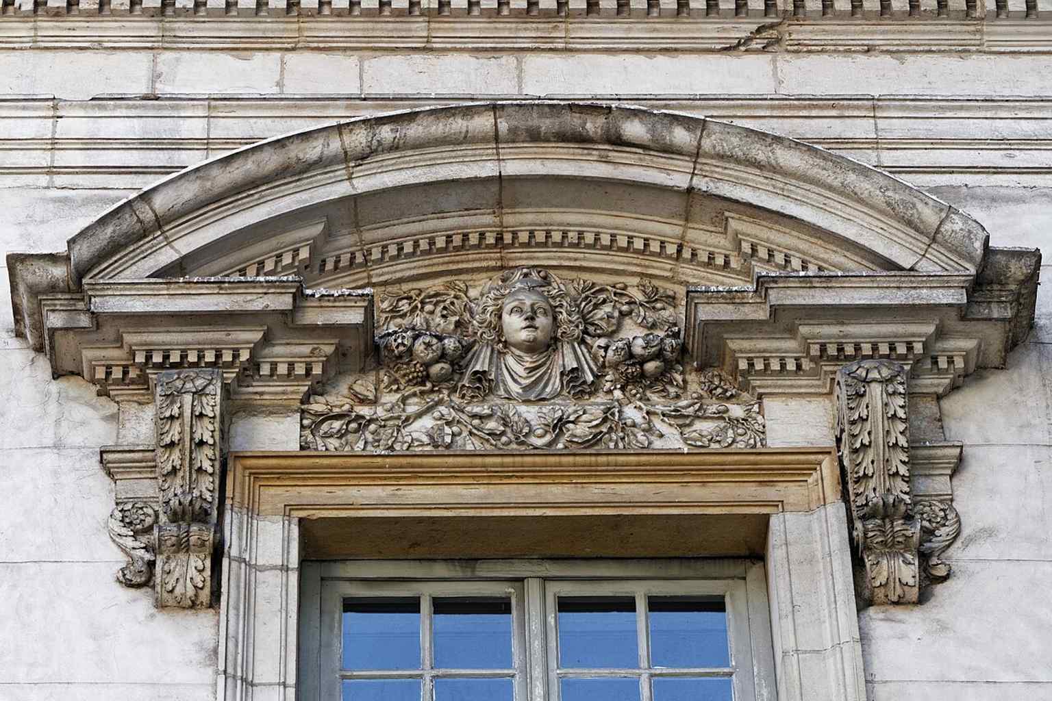 A close look at the facade reveals intricate Renaissance-inspired details, including curved and triangular pediments, mascarons, and garlands, a style that recalls Hugues Sambin's work.