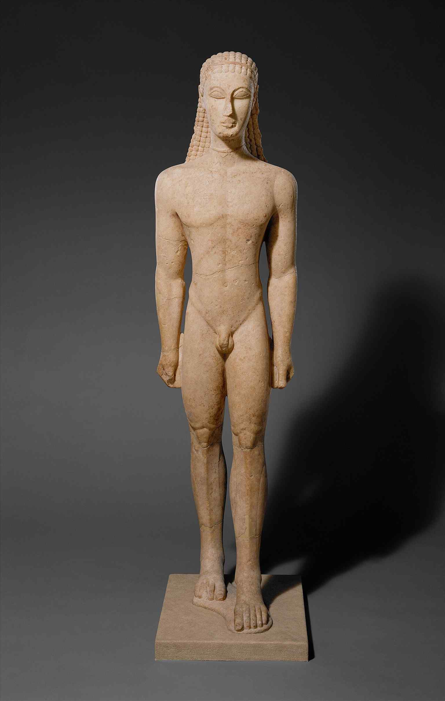 A clear museum view of the youth statue that helps show its idealized, geometric body and the detached limbs carved from one block of Naxian marble.