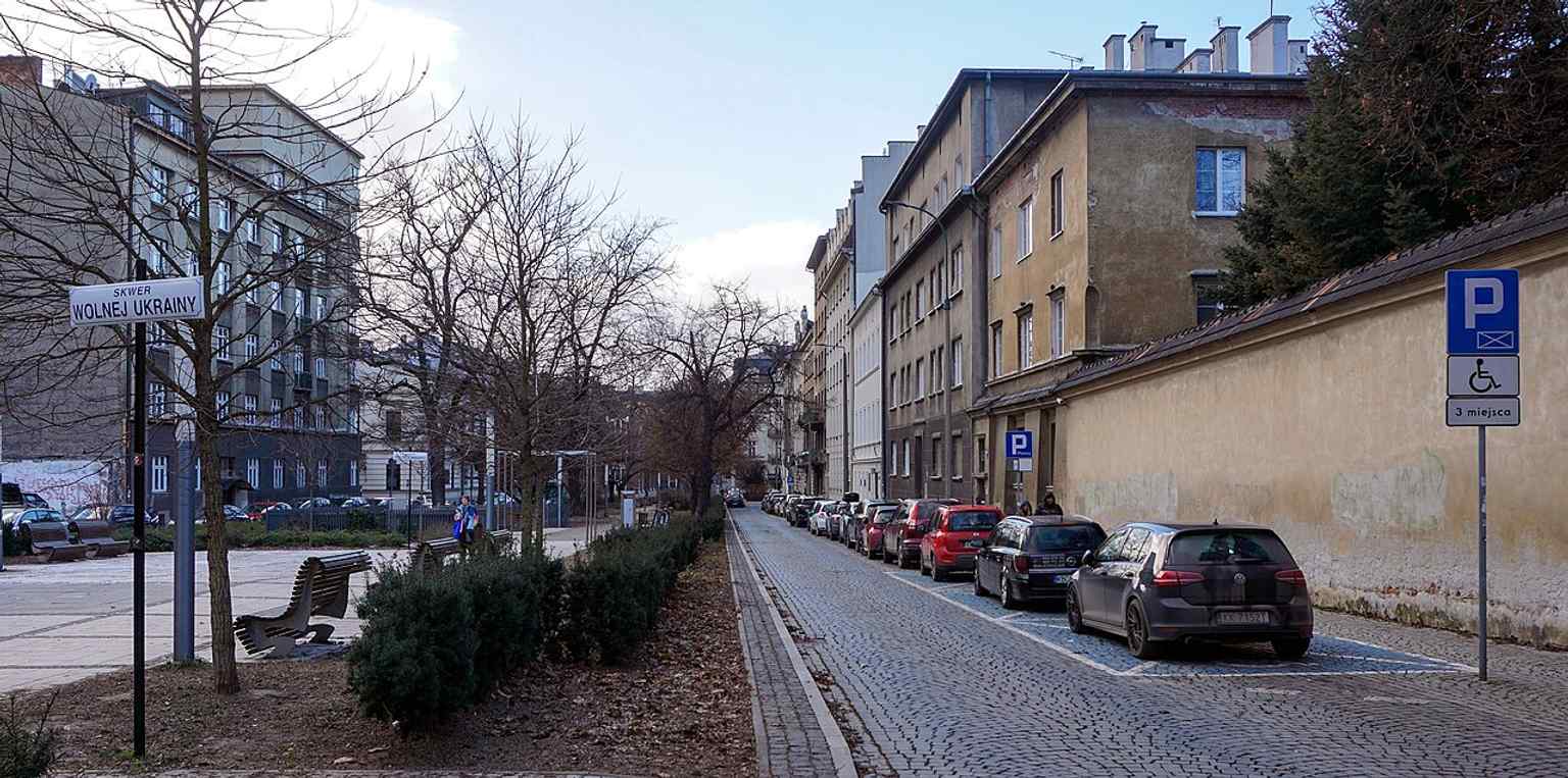 Another street-level view of Biskupia Street in Kraków, useful for showing the long open corridor and the green central strip of the former square.