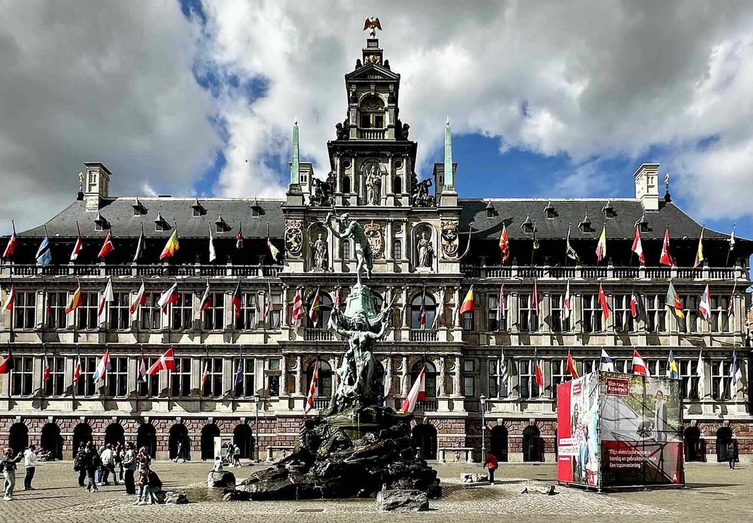 A clear modern view of the Brabo Fountain beside Antwerp City Hall, showing how the statue faces the square rather than the Scheldt.
