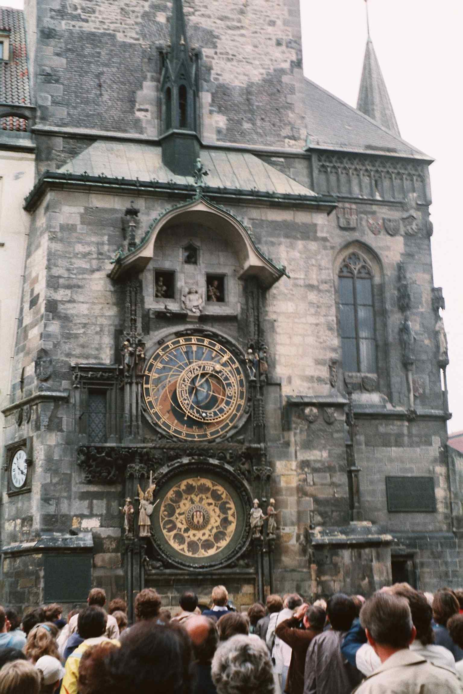 Das detaillierte Kalenderblatt, ursprünglich von Josef Mánes, zeigt Allegorien der Monate und Tierkreiszeichen mit dem mittelalterlichen Prager Wappen in der Mitte.