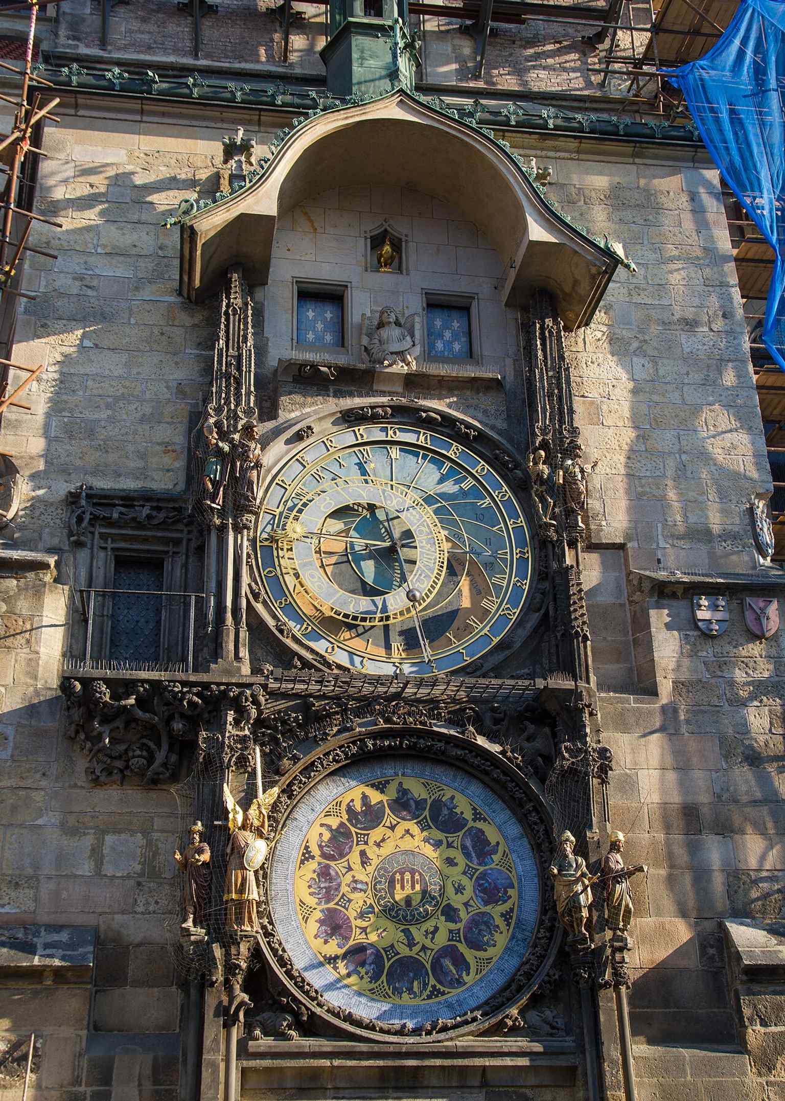 Die zwei Fenster oberhalb des Zifferblatts, in denen jede Stunde die zwölf Apostel erscheinen – eine Ergänzung aus dem 19. Jahrhundert, die mit dem Krähen des goldenen Hahns abschließt.