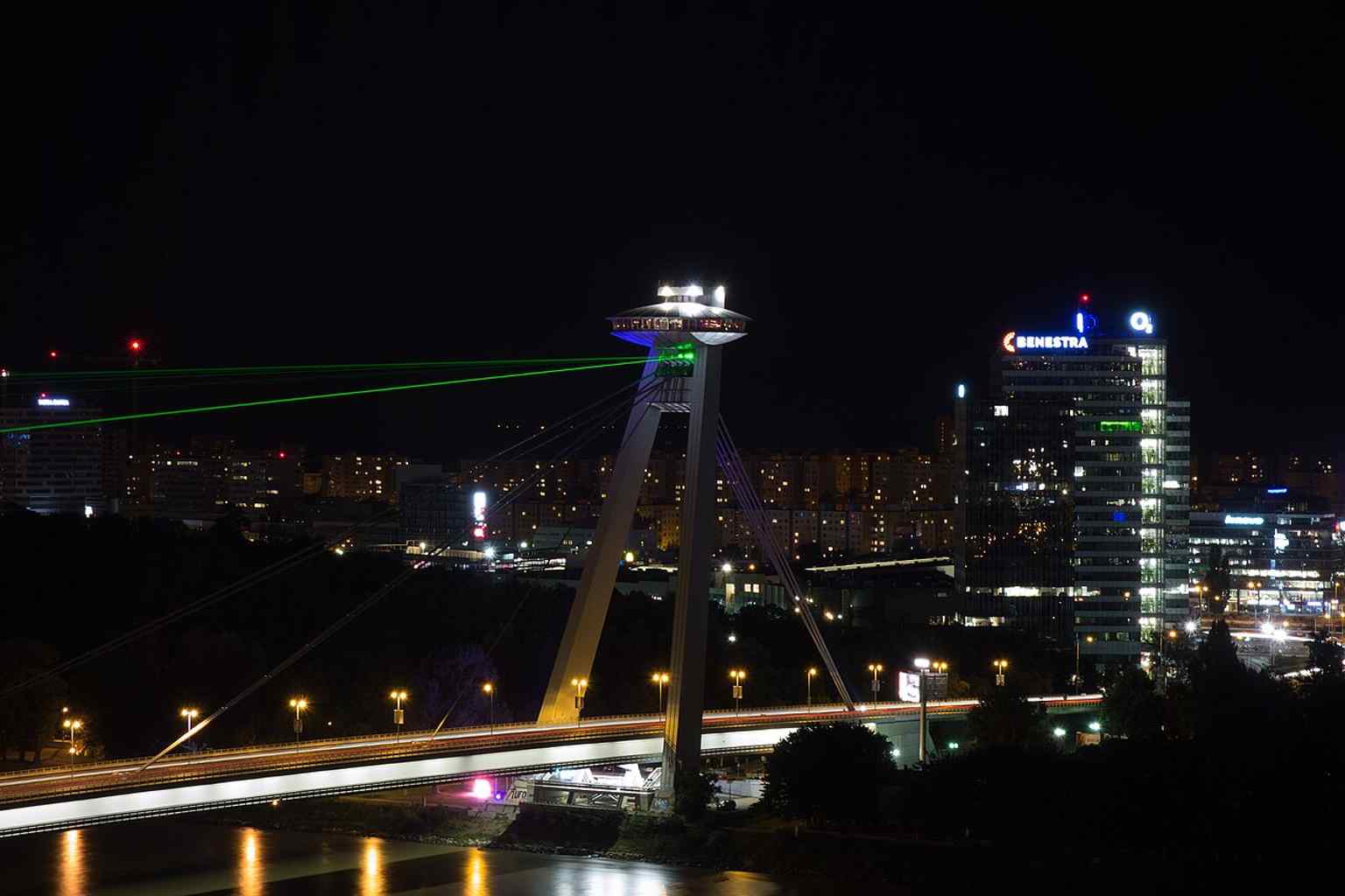 A zoomed night city view featuring the UFO tower, highlighting the restaurant and observation deck perched 85 meters above the Danube.