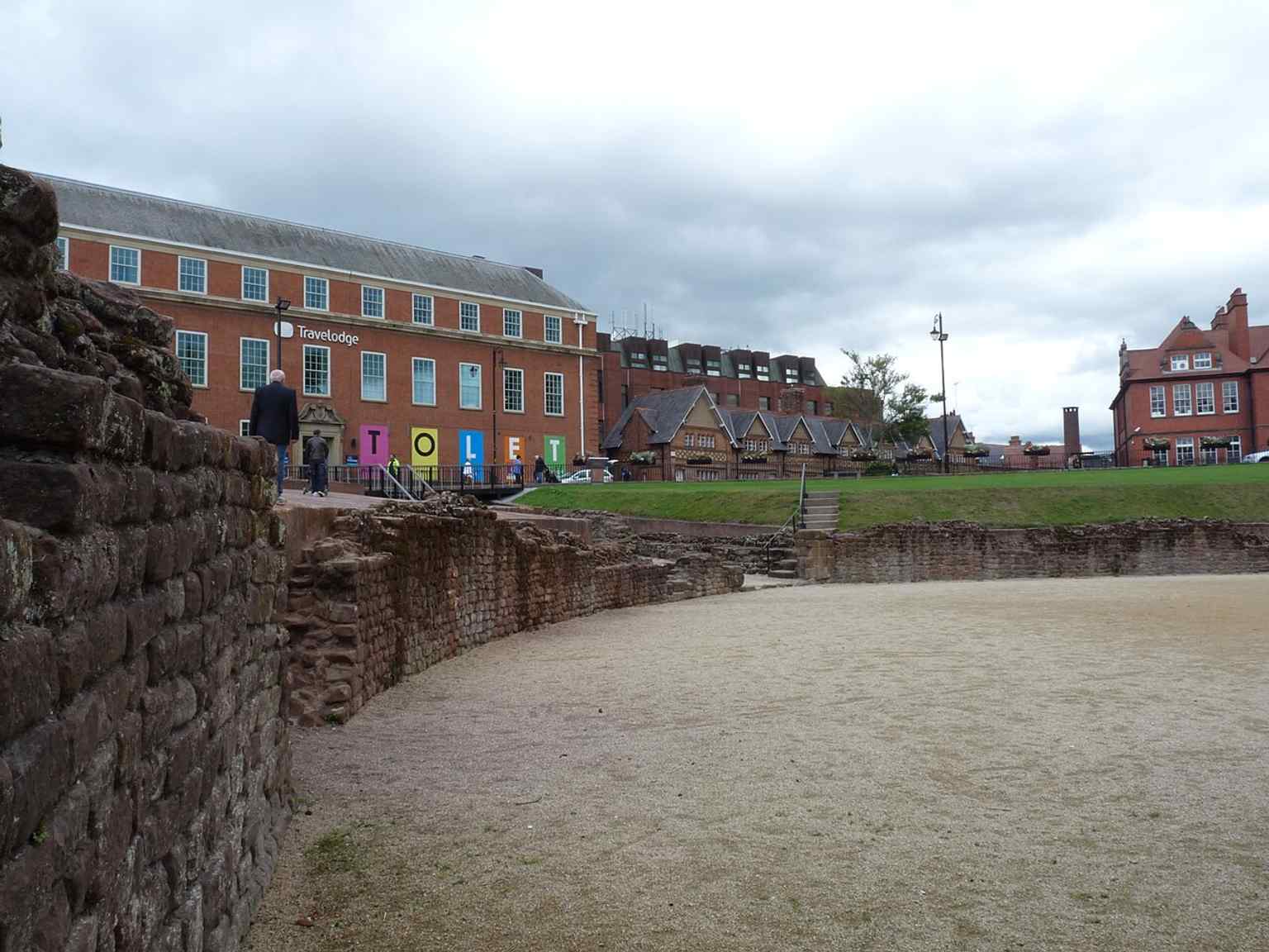 Looking across the western edge of the excavated arena floor, a good angle for explaining the curved seating bank and the exposed northern side.