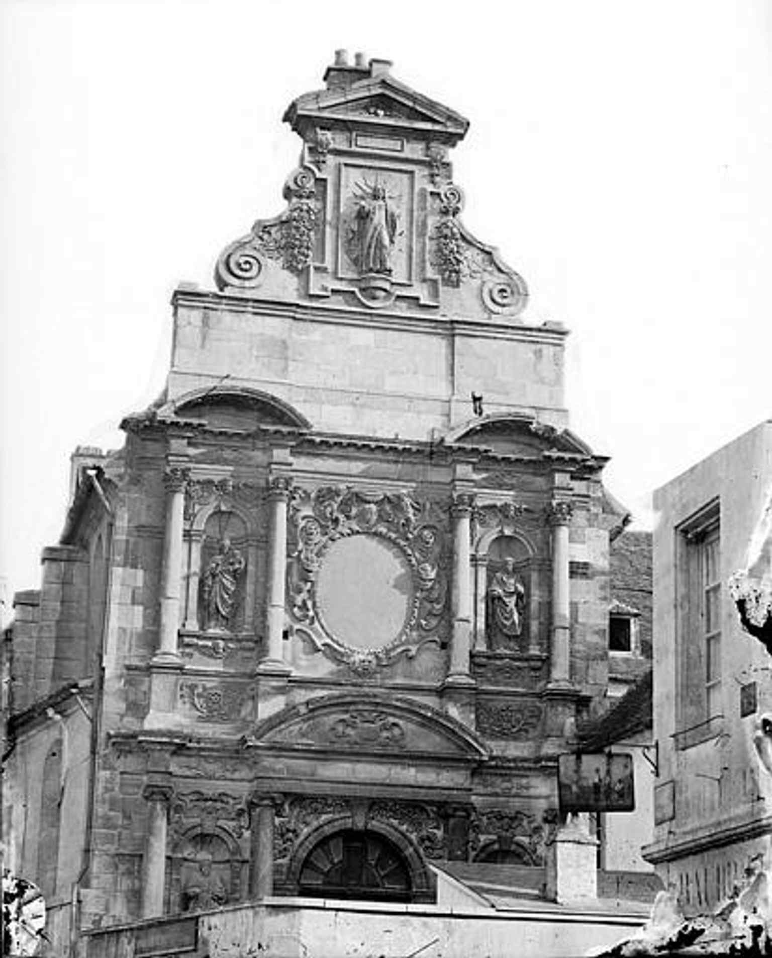 This 1919 historical image captures the upper section of the facade, offering a glimpse of the statue of Christ at its pinnacle from an earlier era.