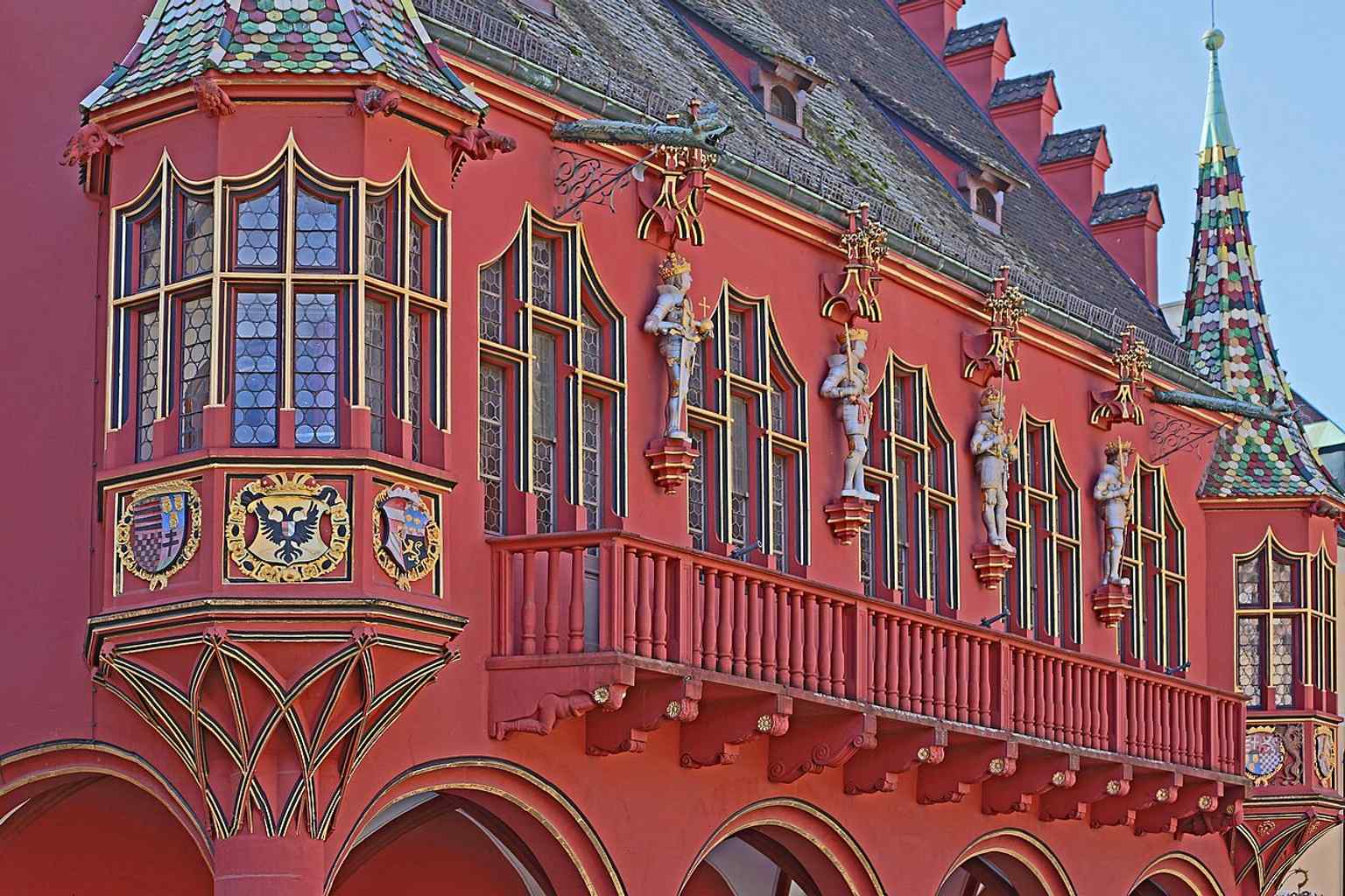 A full view of the Historic Department Store’s red Münsterplatz façade, the landmark’s most famous side facing Freiburg Minster.