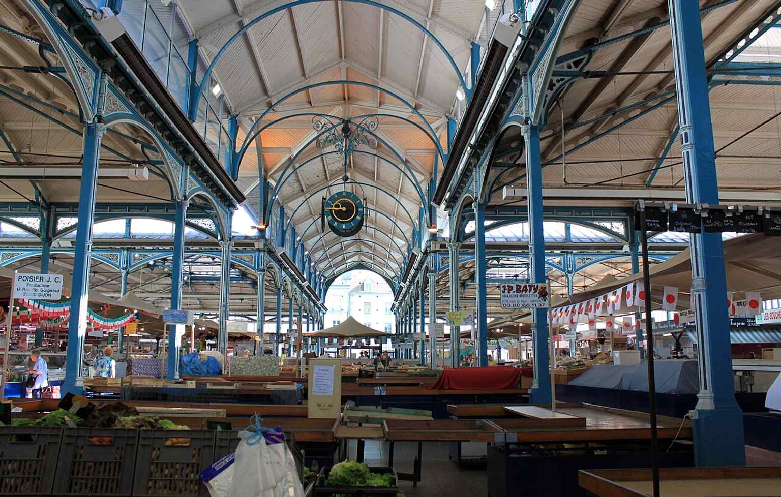 Explore the vibrant interior of the Central Markets, where the metallic architecture from 1873-1875 frames the lively market activity held Tuesdays, Thursdays, Fridays, and Saturdays.