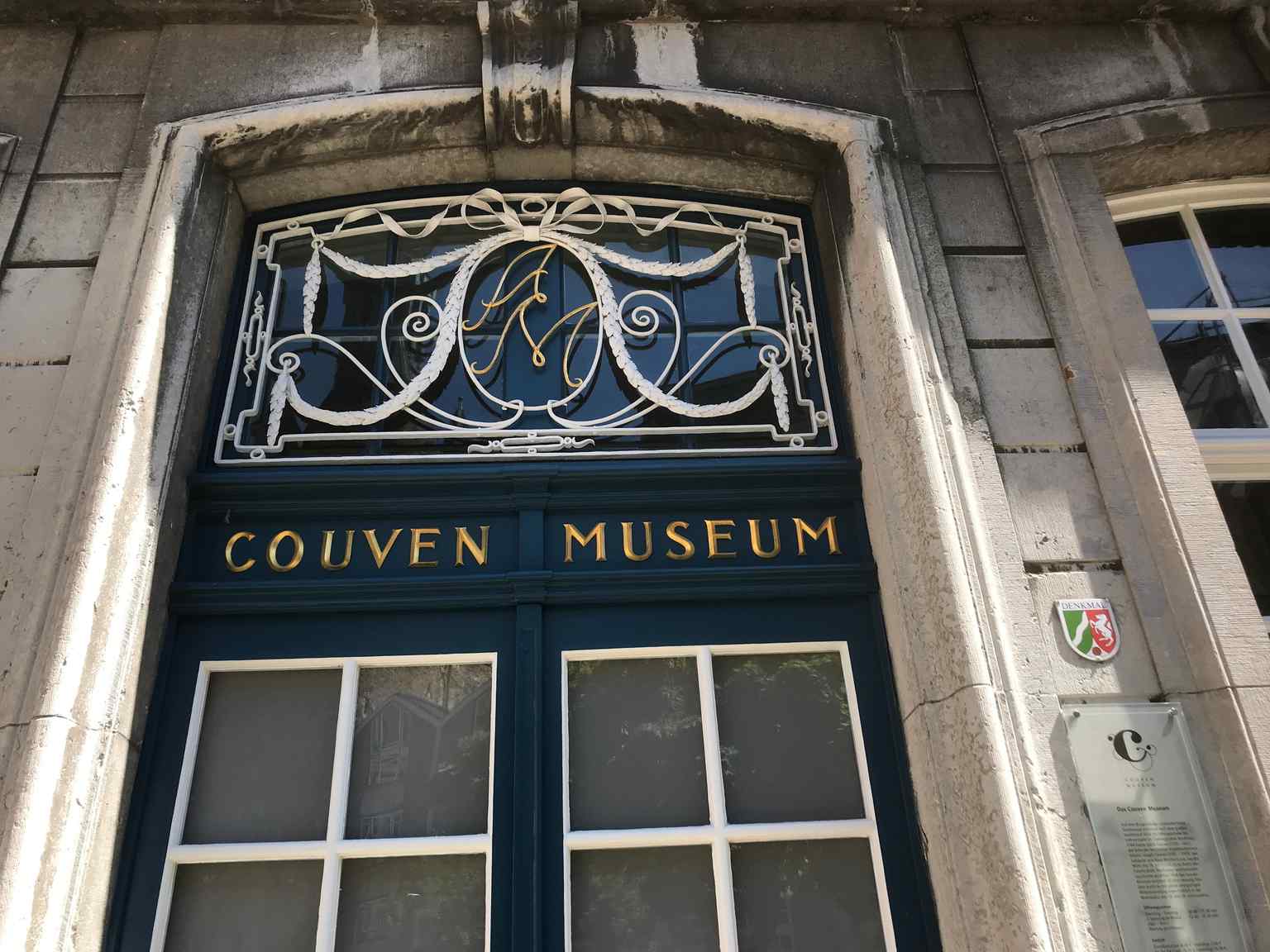 This entrance door features the initials of Andreas Monheim, whose family pharmacy, the Adler-Apotheke, located here, was the birthplace of Germany's first machine-made bar chocolate, leading to the famous 'Trumpf' brand.