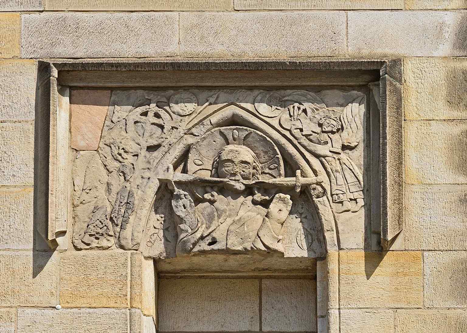 An exterior stone relief on the church, echoing the preserved medieval sculpture around the west and north portals.