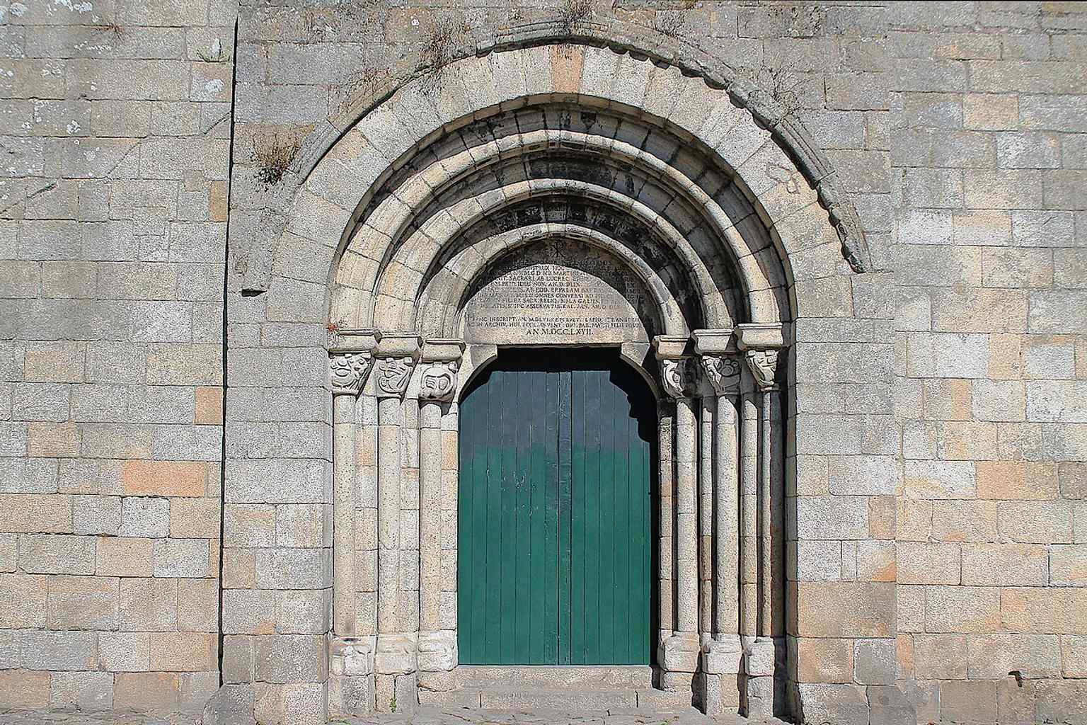 The main west doorway with its Romanesque arches and carved tympanum, where a 1767 inscription later added a legendary founding story.
