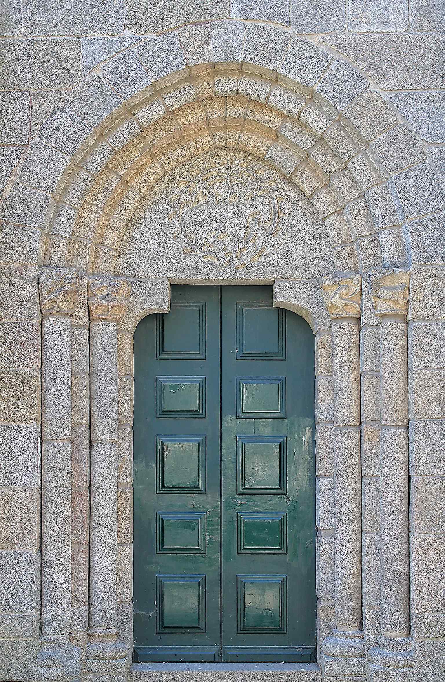 The smaller side doorway shows the church’s repeated Romanesque portico design, with sculpted capitals and a more intimate entrance.