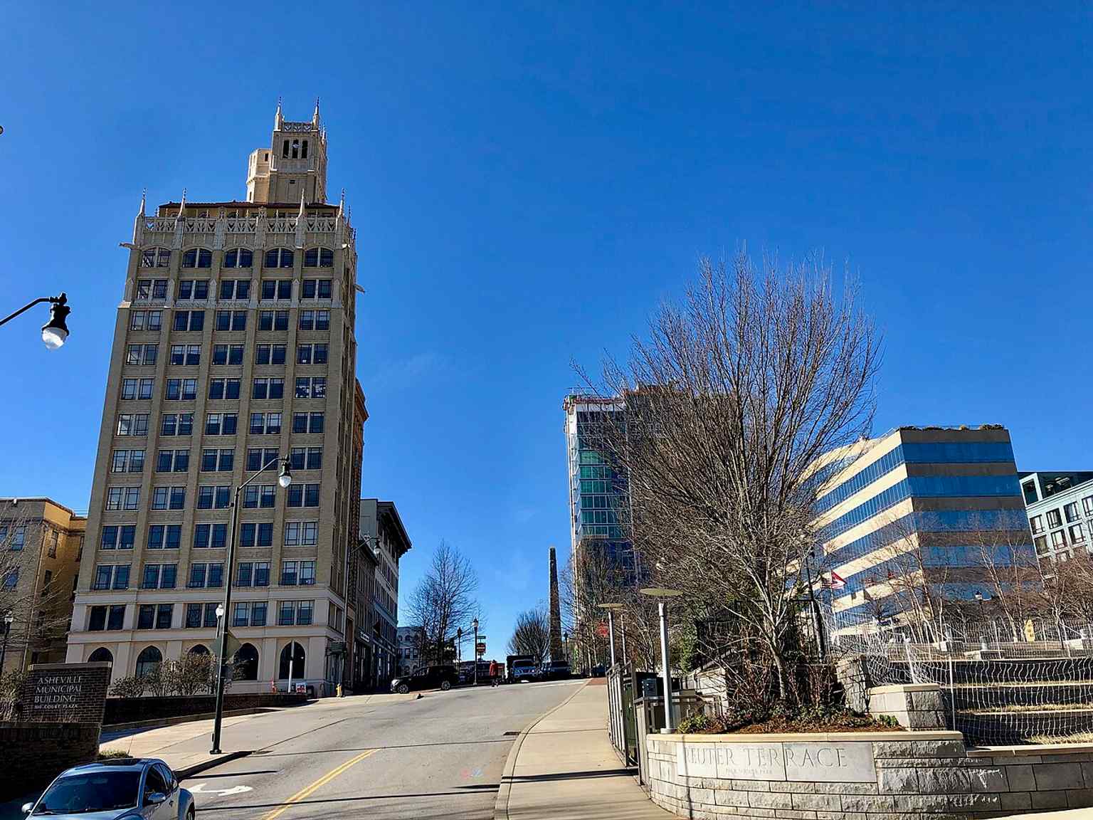 A wide Pack Square view that places the monument in Asheville’s larger downtown setting among modern buildings.