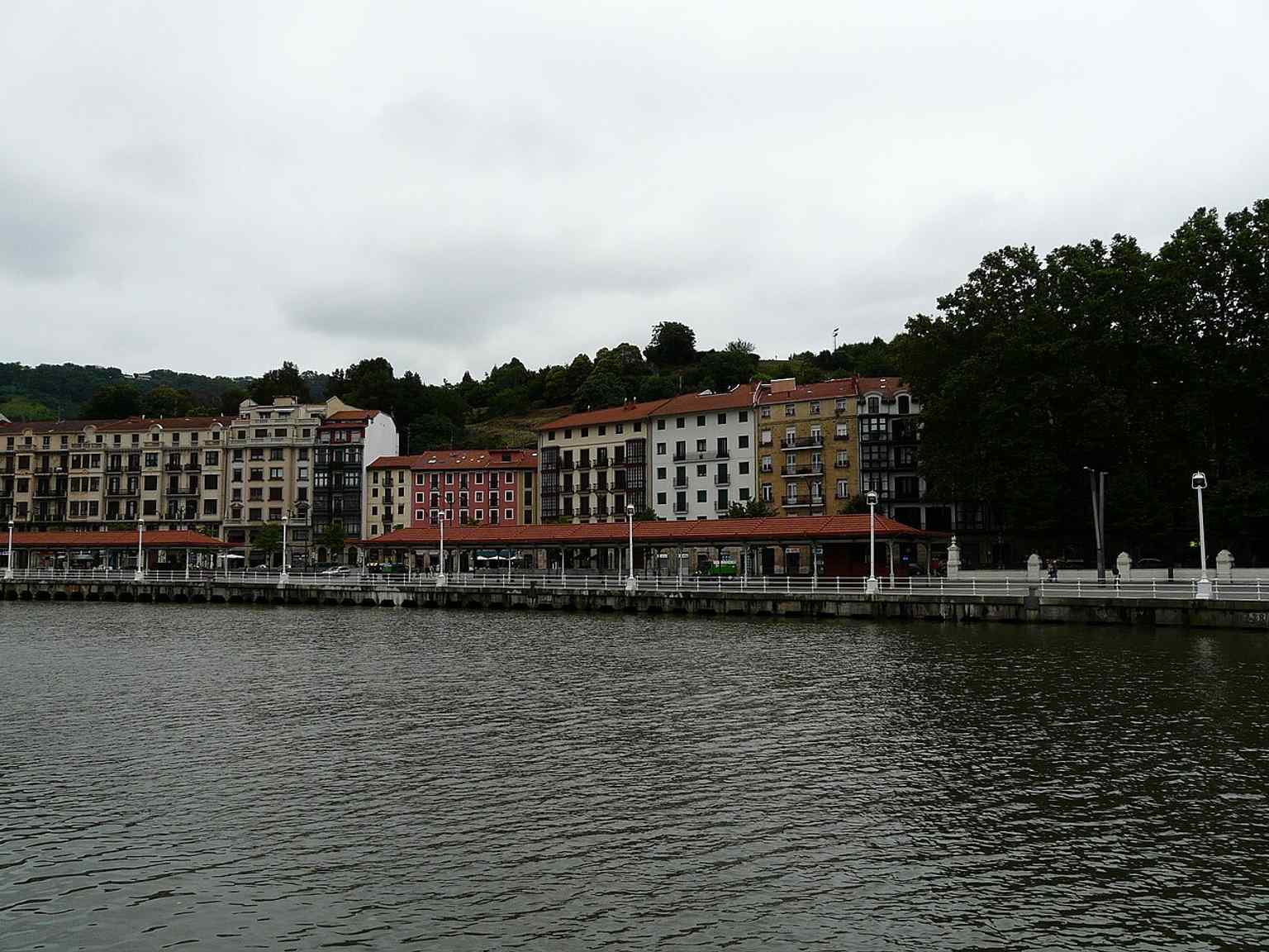 A wide view of El Arenal from across the river, showing its long promenade as the main front of Bilbao’s Old Town beside the estuary.