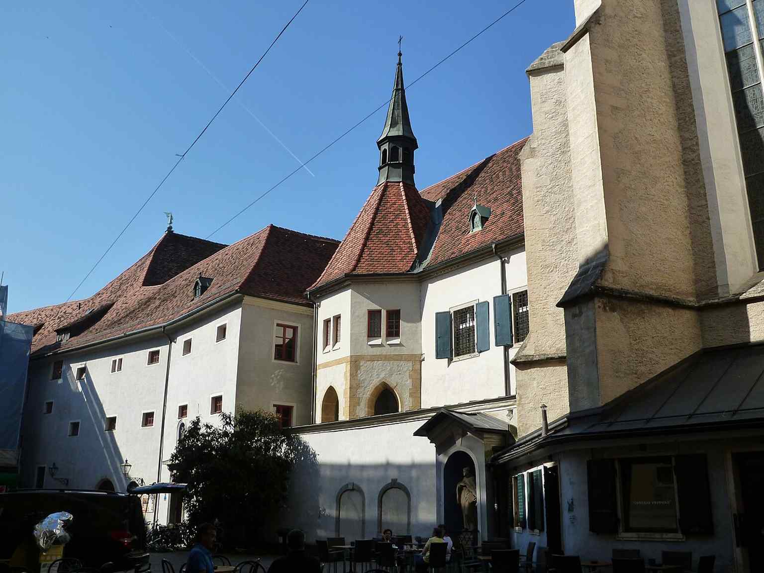 The monastery’s sunlit east side shows how the church and convent are tightly woven into Graz’s old city wall system.