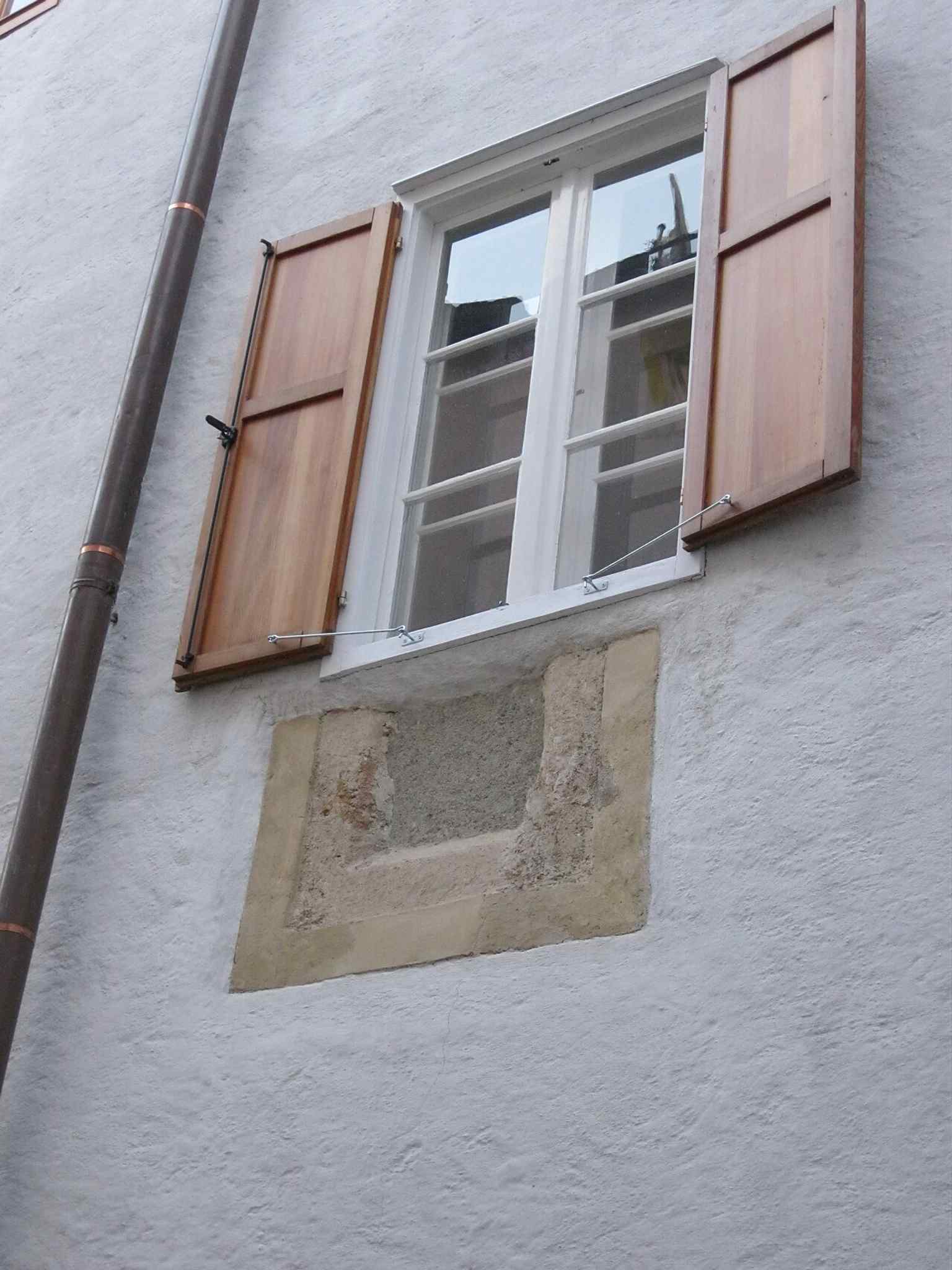 The wall’s loopholes and masonry hint at the building’s defensive past, including the former Wehrturm mentioned in the history.