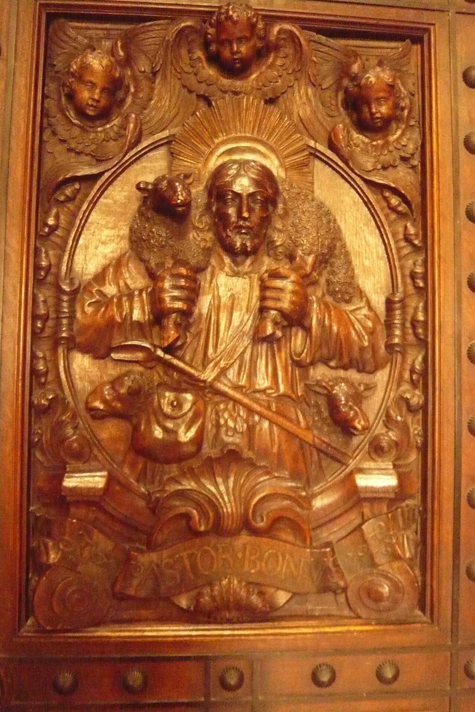 A carved sacristy doorway with a Good Shepherd motif, showing the Spanish-style ornament that fills the church’s interiors.