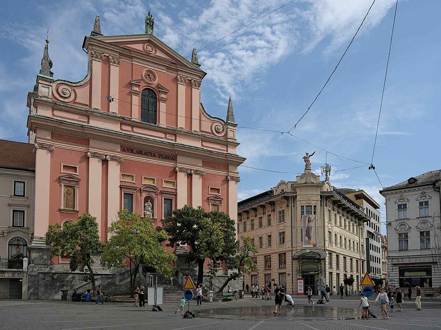 A summer view of Prešeren Square, featuring the Urbanc Department Store with its distinctive Art Nouveau facade, a building designed in 1902 and noted for combining strict Viennese Secession with lighter French Art Nouveau elements.