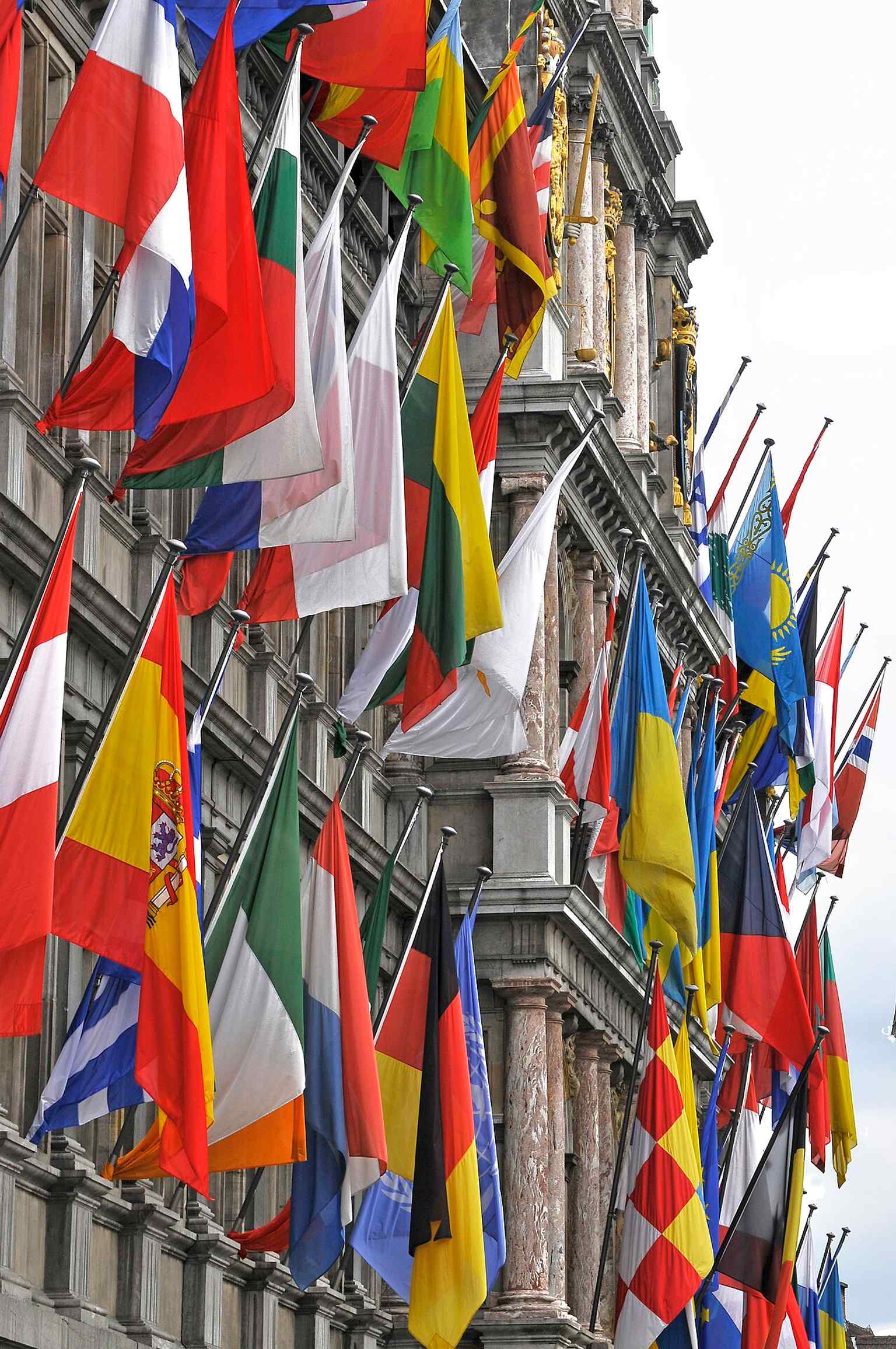 The main façade with flags captures the building’s ornate Renaissance front, including the central tower that replaced older Gothic plans.