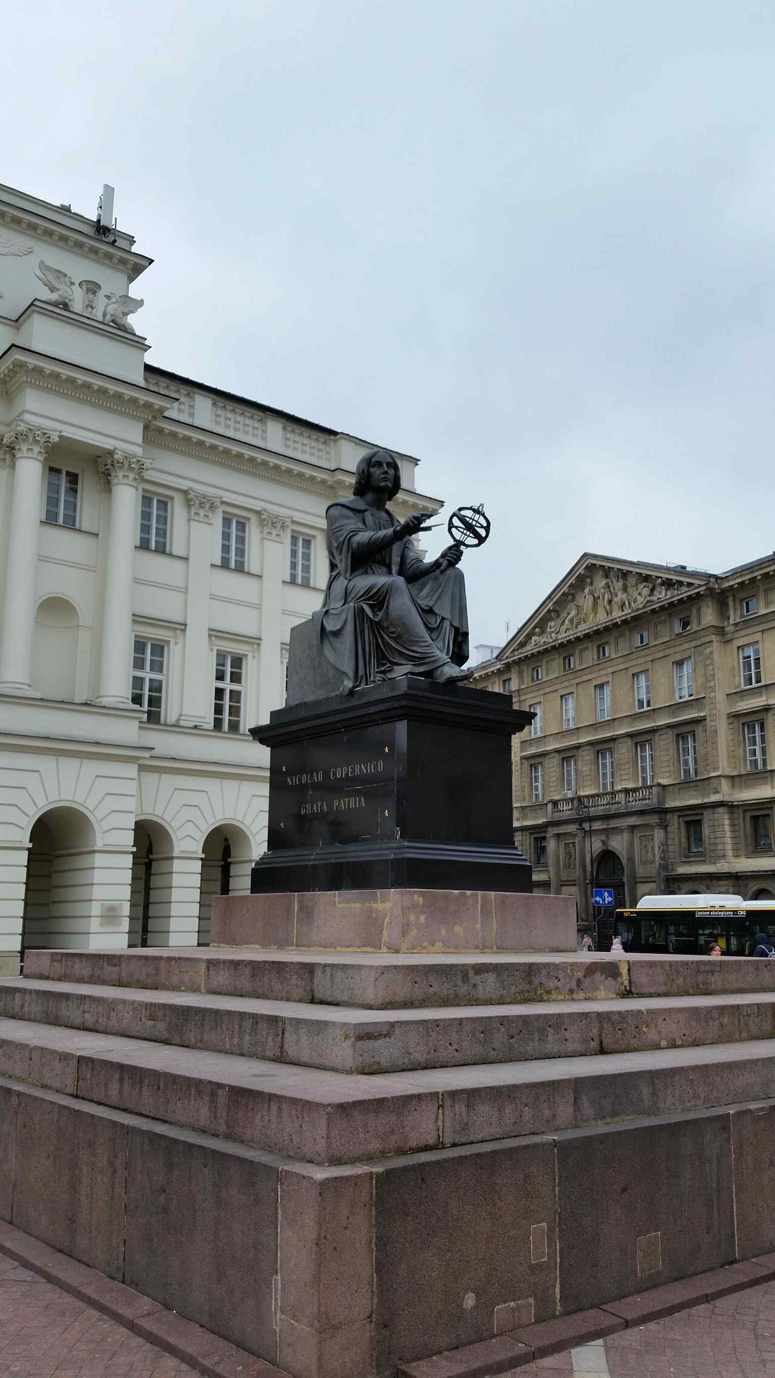A tight vertical view of the statue that highlights the bronze figure and pedestal details more than the surrounding square.