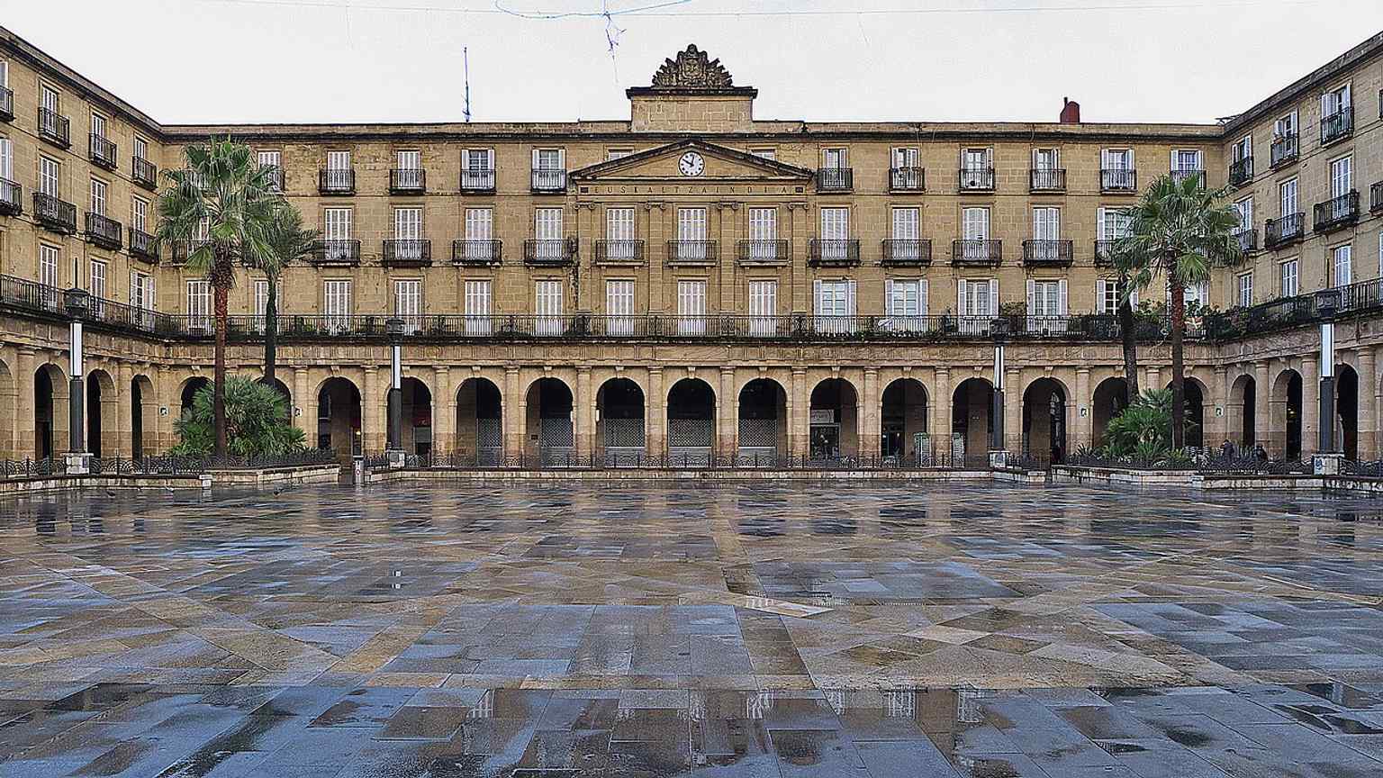 The neoclassical façade of Plaza Nueva, now home to Euskaltzaindia, reflects the square’s long civic history from government seat to language stewardship.