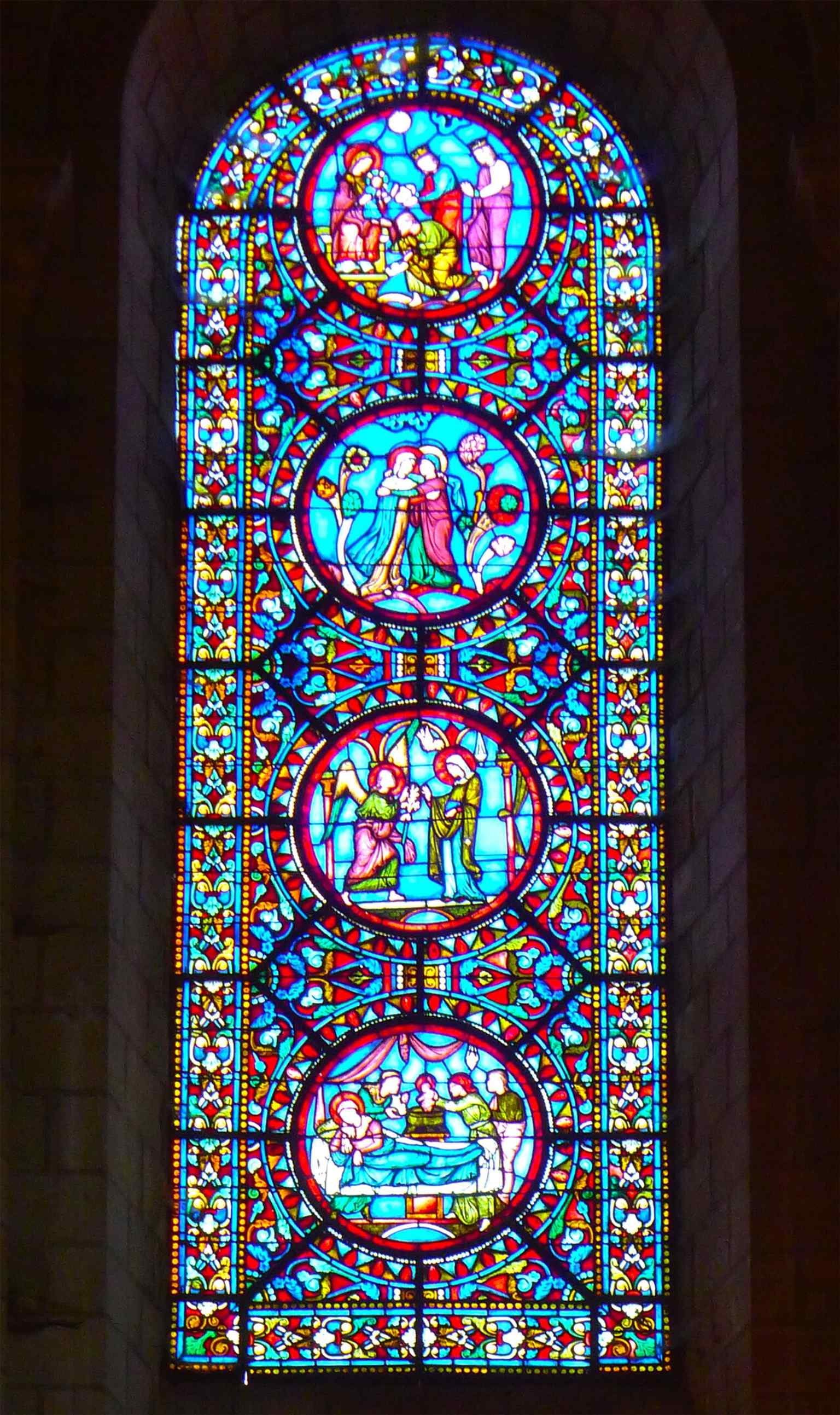 One of the choir's stained-glass windows by Thierry fils (1860s), designed in an 'archaeological' style with deep blues and medallion compositions to evoke a medieval atmosphere.