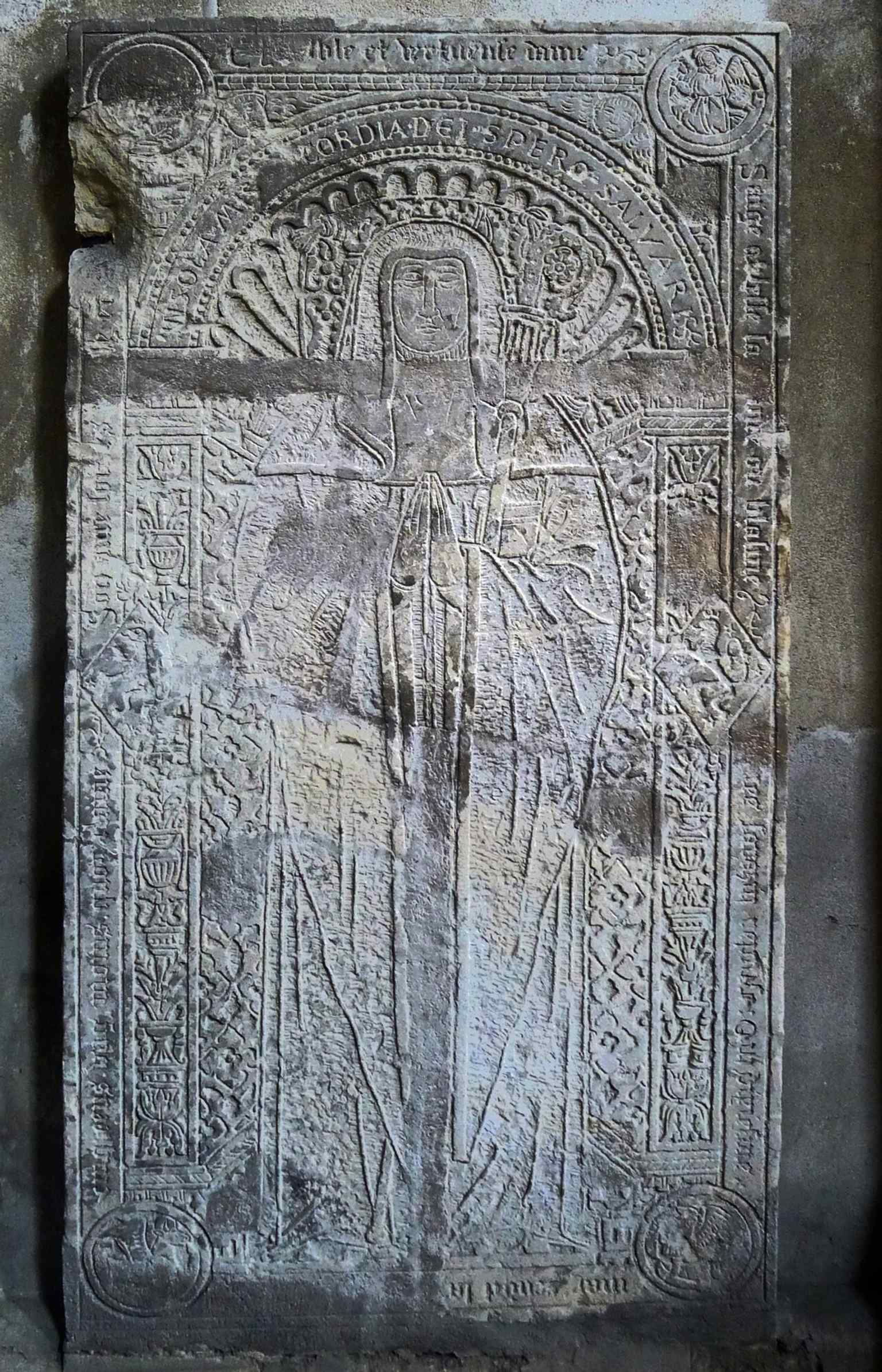 The limestone tombstone of Renée Sarazin, an abbess of Ronceray from 1493 to 1499, found within the ancient staircase, symbolizing the abbey's historical dominance over the parish.