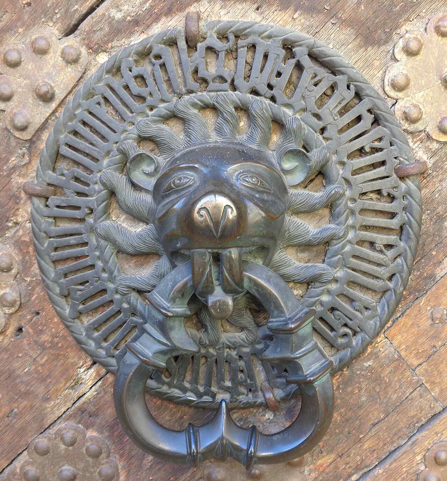 The left-hand door hammer from the main portal — a medieval bronze fitting that turned the entrance into a display of status and sacred wording.