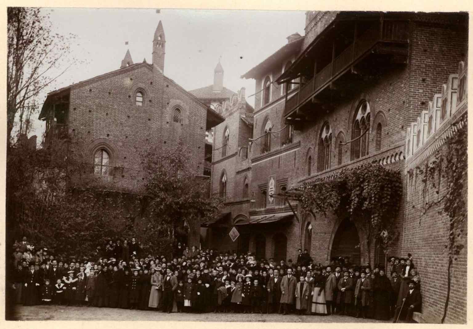A large historical gathering in the village square in 1899, evoking the extravagant theatrical inauguration that originally brought the illusion to life.