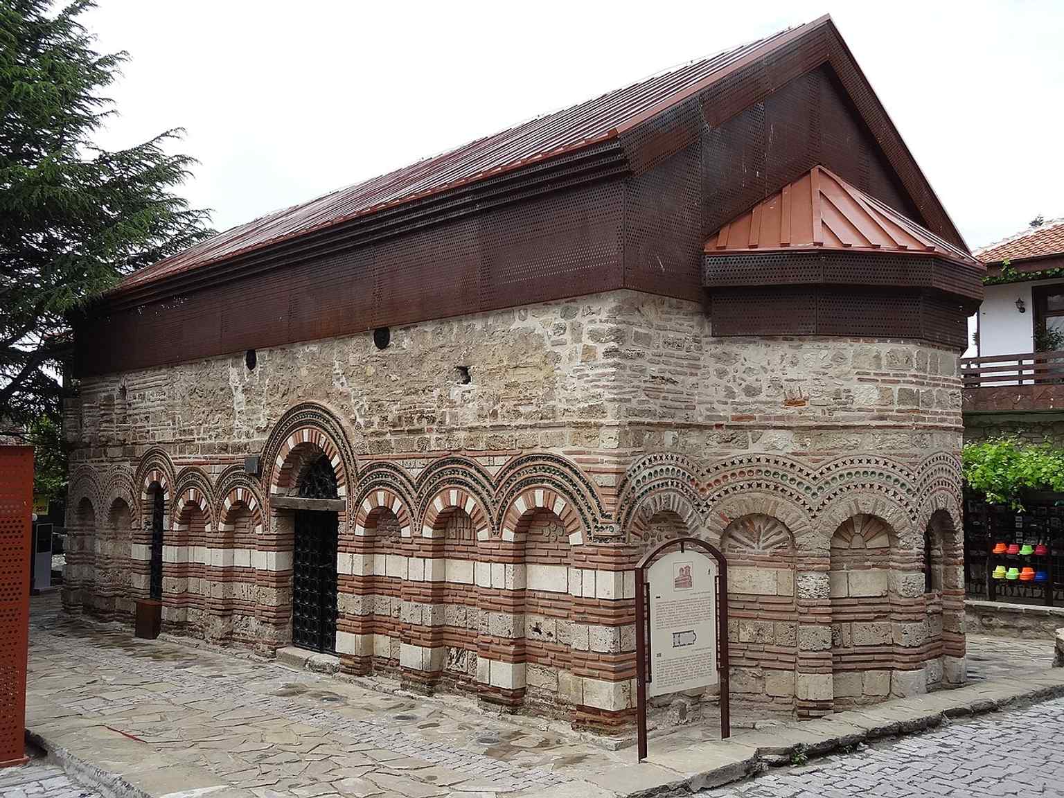 The restored church exterior in Nesebar, showing the medieval brick-and-stone walls that once carried richly decorated blind arches.