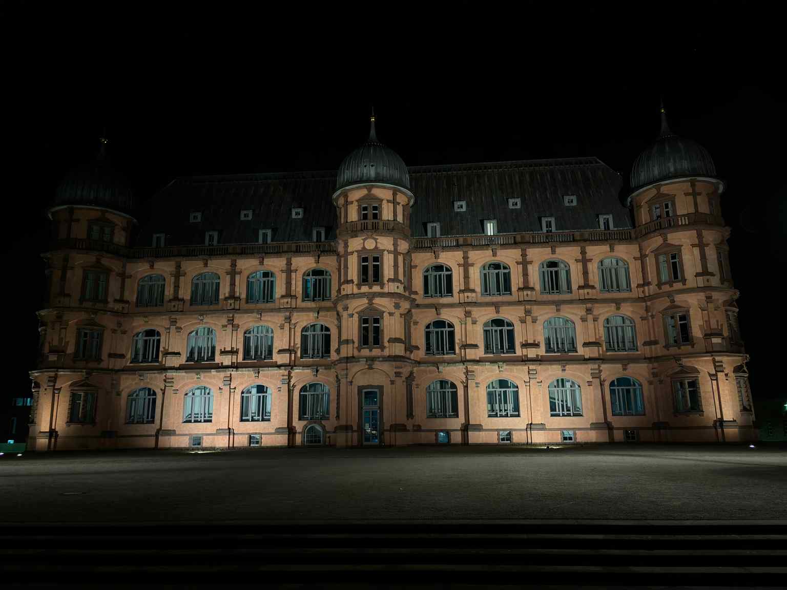 Schloss Gottesaue illuminated at night, hinting at its modern use for events like open-air cinema, which even hosted actor Terence Hill in 2018.