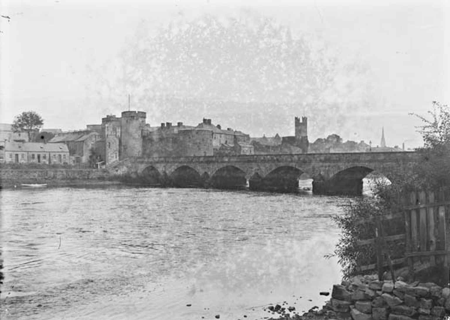 A historical photograph from the early 20th century, showing the seven-arched Thomond Bridge which was built in 1836, incorporating the pier foundations of the earlier structure.