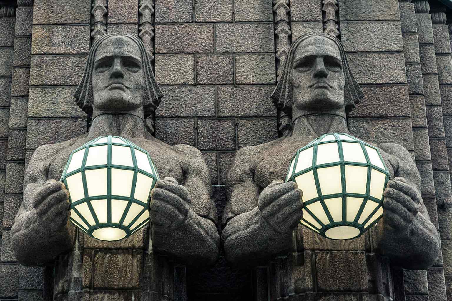 A wide view of Helsinki Central Railway Station, the Eliel Saarinen landmark whose main entrance is guarded by the Lantern Bearers.