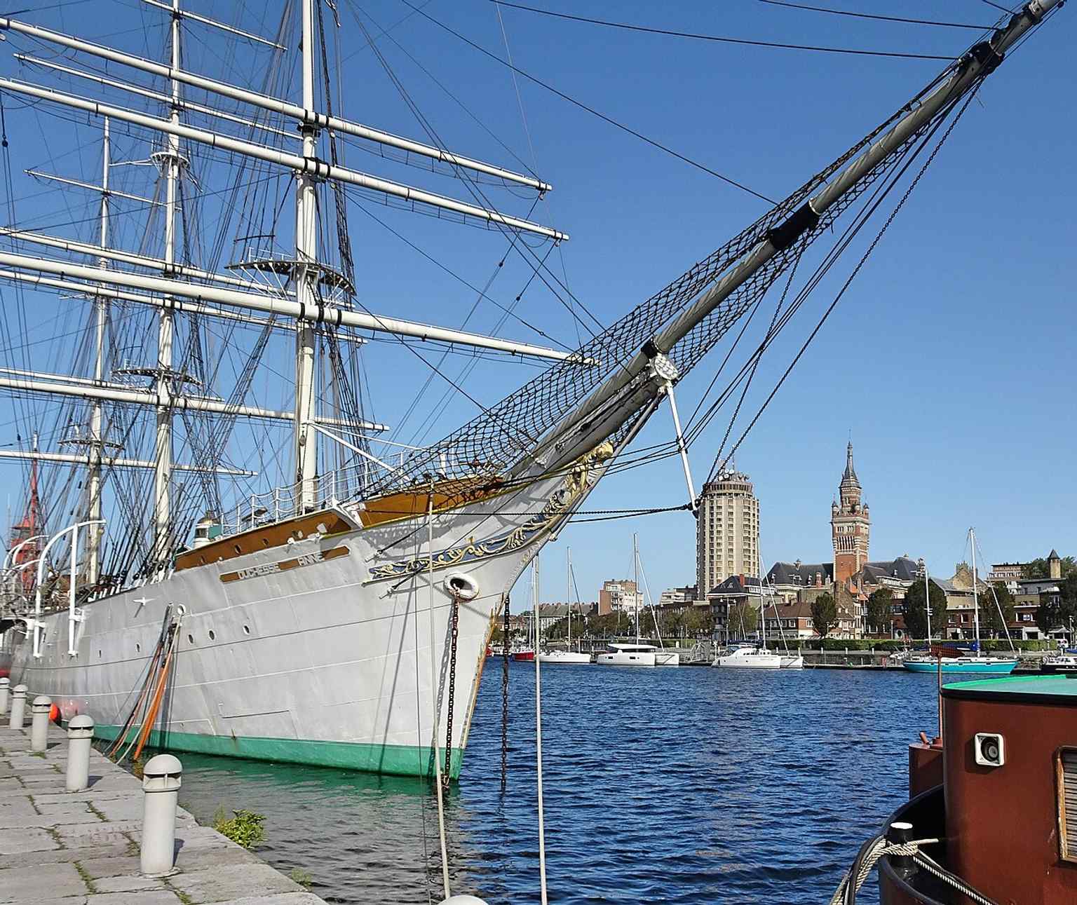The town hall beside the three-masted Duchesse Anne, tying the building to Dunkirk’s port and seafaring identity.