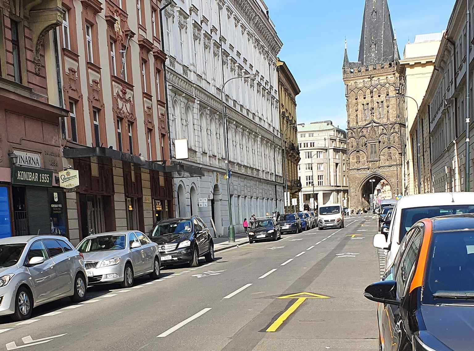 A modern view down Hybernská Street, showcasing the Powder Tower's prominent position at the intersection with Na Příkopě and Republic Square.