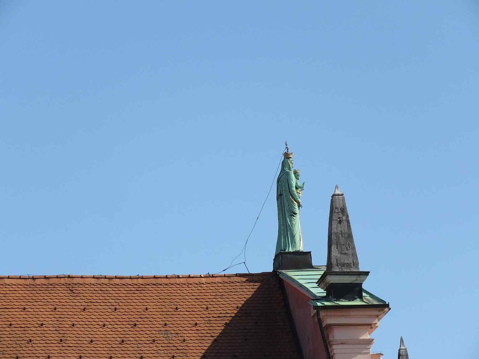 The largest copper Madonna statue in Ljubljana crowns the church's pediment, replacing an older wooden "Black Madonna" in 1858.