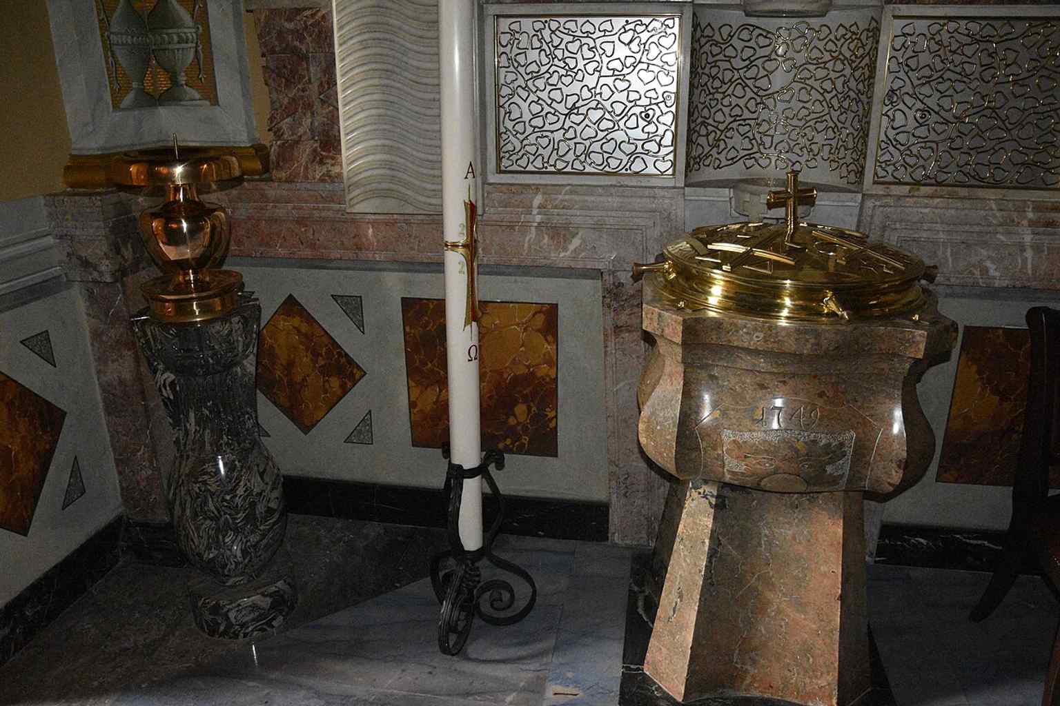 This ornate side chapel, featuring a baptismal font and rich altar equipment, showcases the early Baroque design of the church's single-nave hall with multiple chapels.