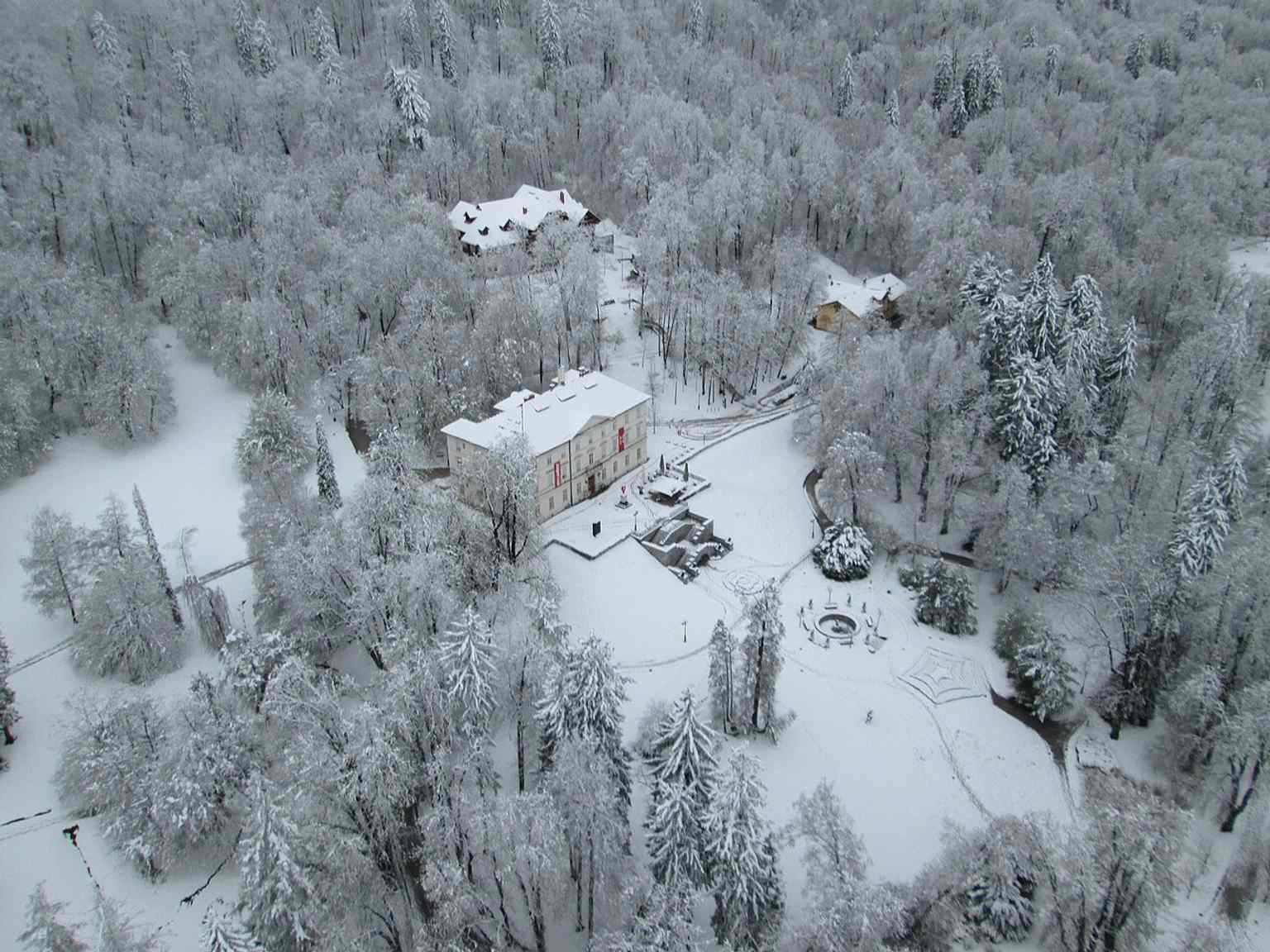 An aerial view of Tivoli Castle, also showing Švicarija (the former Hotel Tivoli) behind it, nestled at the foot of Rožnik hill, as the castle is prominently visible from the city center.