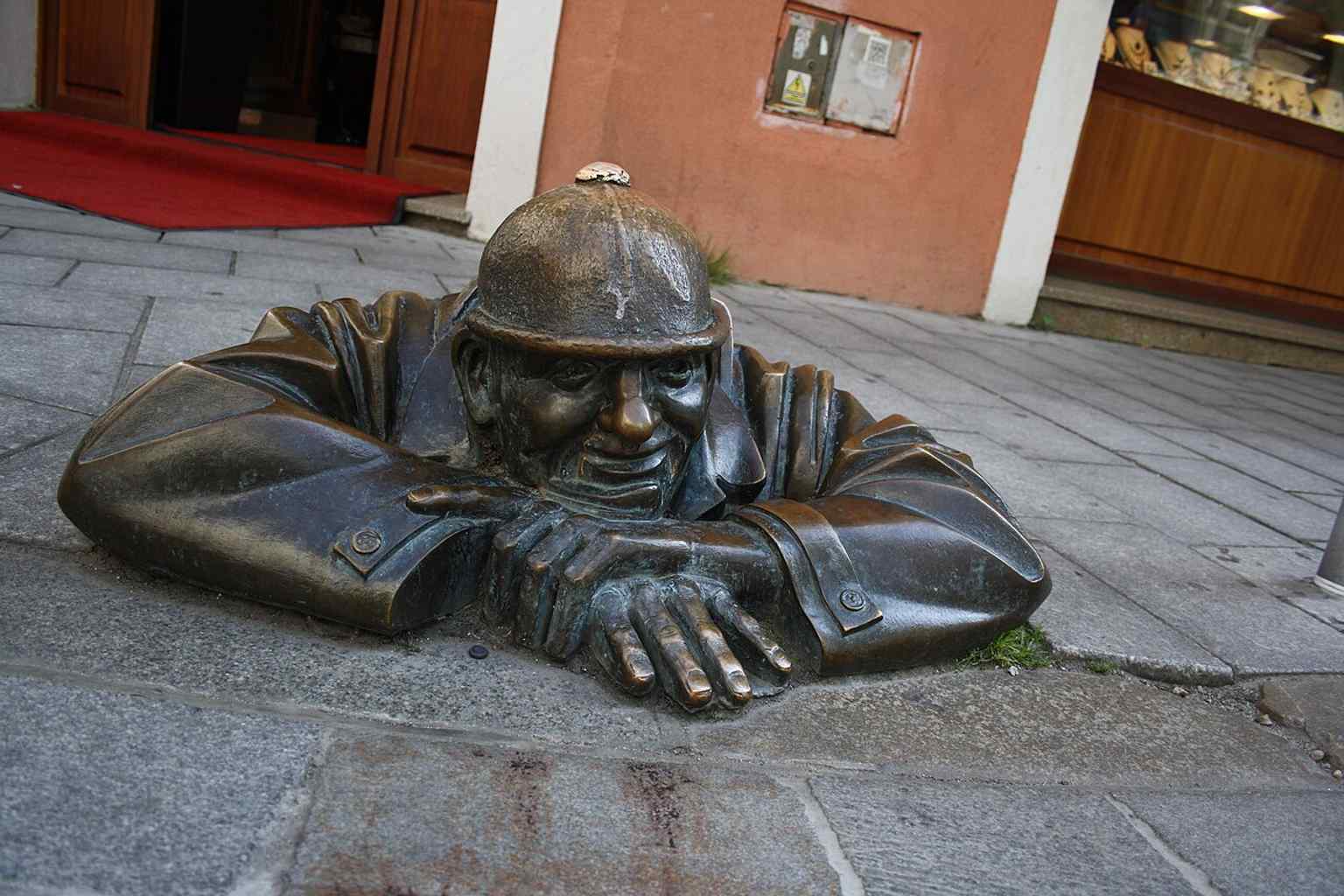 Čumil peeking from the pavement in the Old Town — one of Bratislava’s most photographed street sculptures.