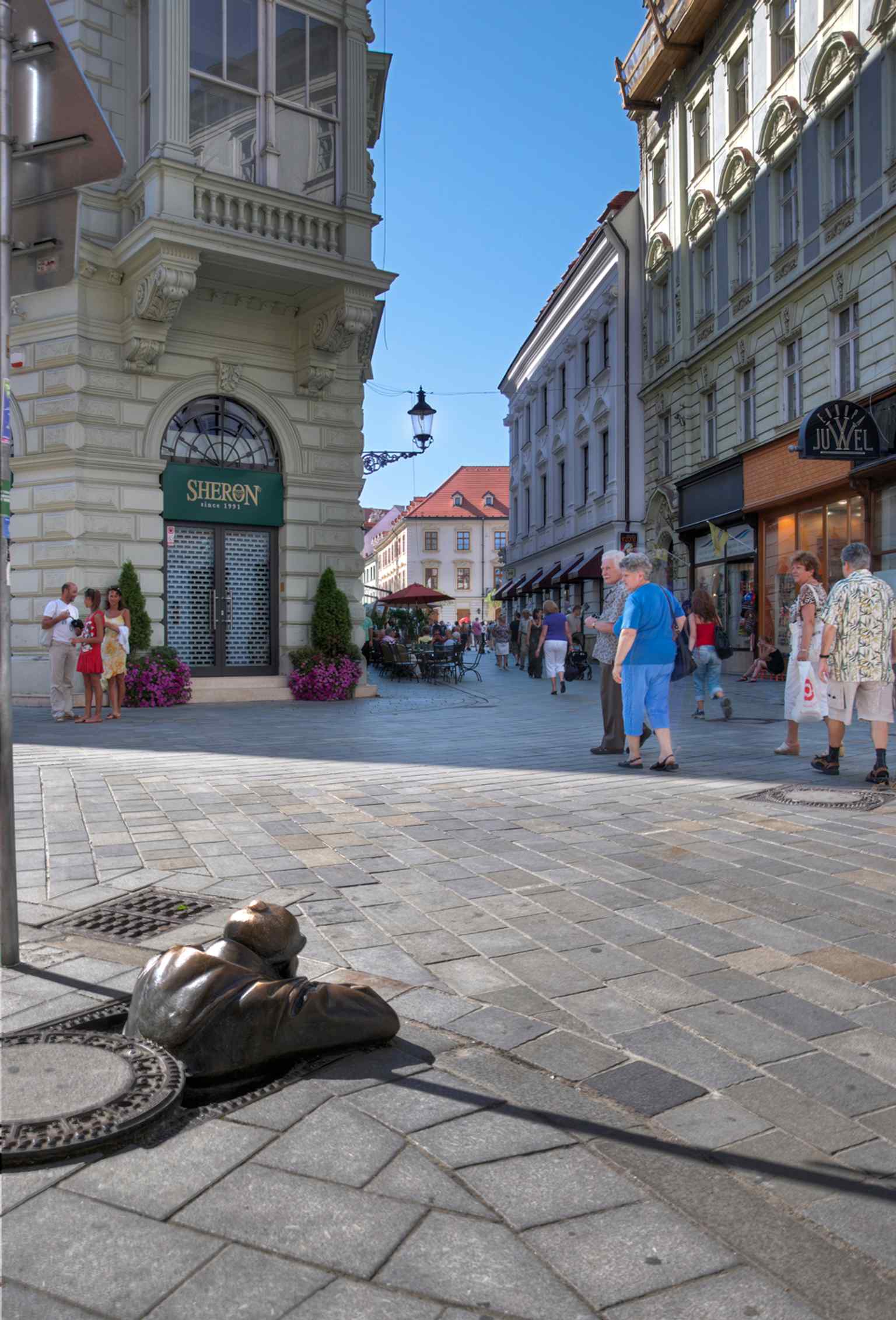 Tourists gathering around Čumil, reflecting the ritual of crowding in for photos at Bratislava’s best-known statue.
