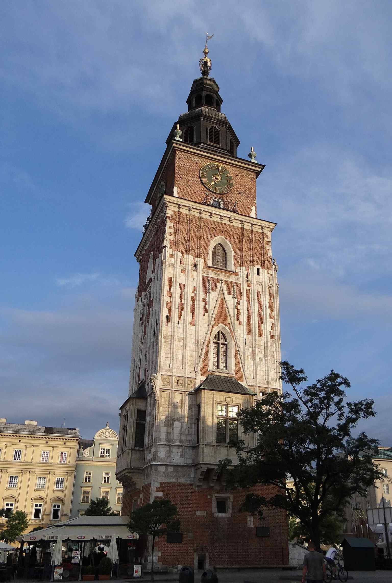 A tall, detailed facade shot that captures the tower’s 70-metre height and its presence beside the Main Square’s historic architecture.