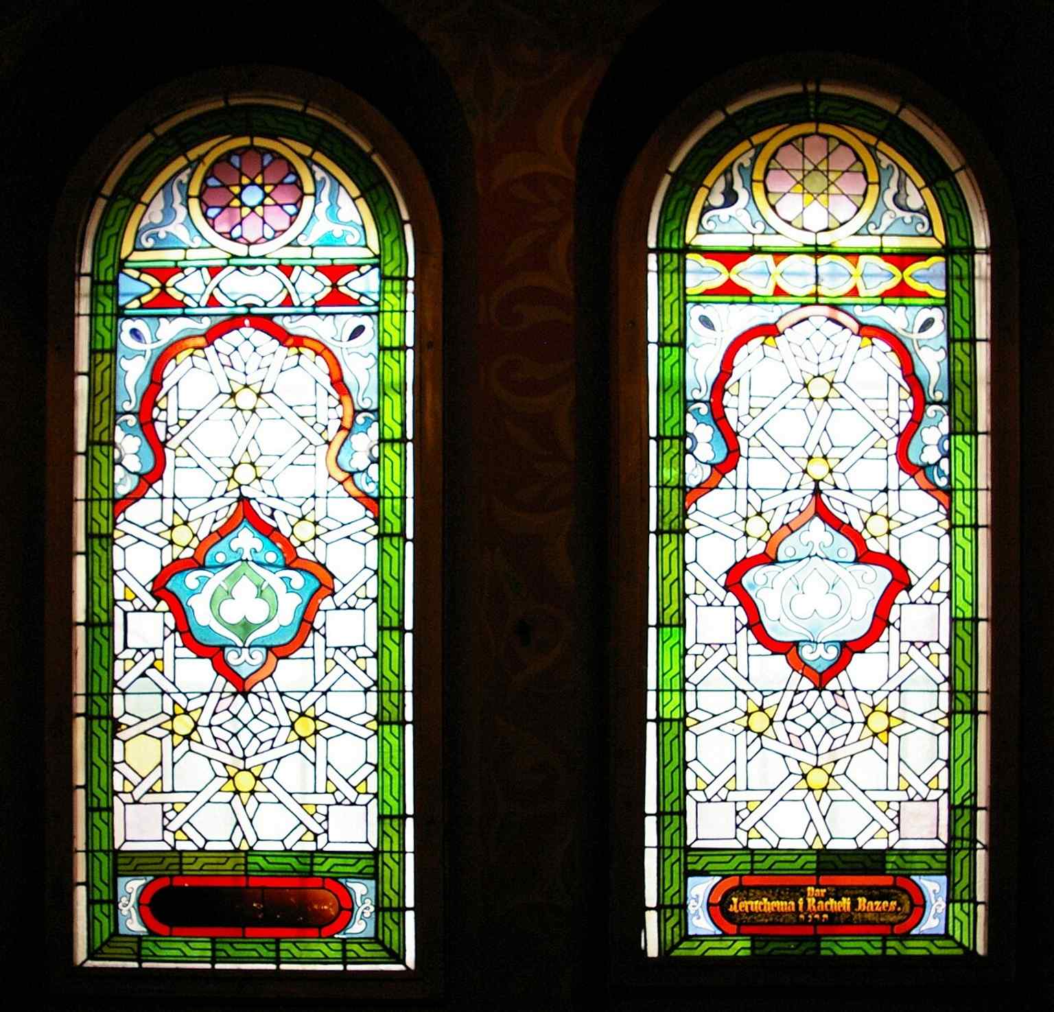 Stained-glass panes that still carry donor names, preserving the people who funded Tempel’s original progressive congregation.