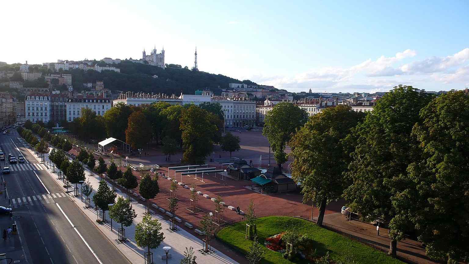 A clean street-level view of the square’s wide, open surface and tree-lined edges, matching Bellecour’s role as a major public meeting place.