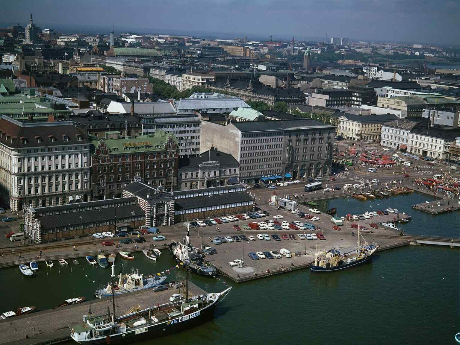 The hall in the 1970s, when the surrounding harbor rail and waterfront showed how closely the market hall was tied to Helsinki’s port life.