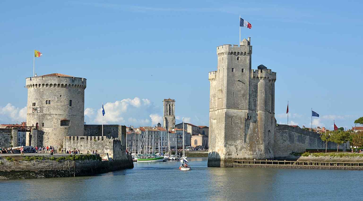 The harbor channel framed by Saint Nicholas Tower and the Chain Tower — exactly the dramatic gate that once closed off the port with a tethered chain.