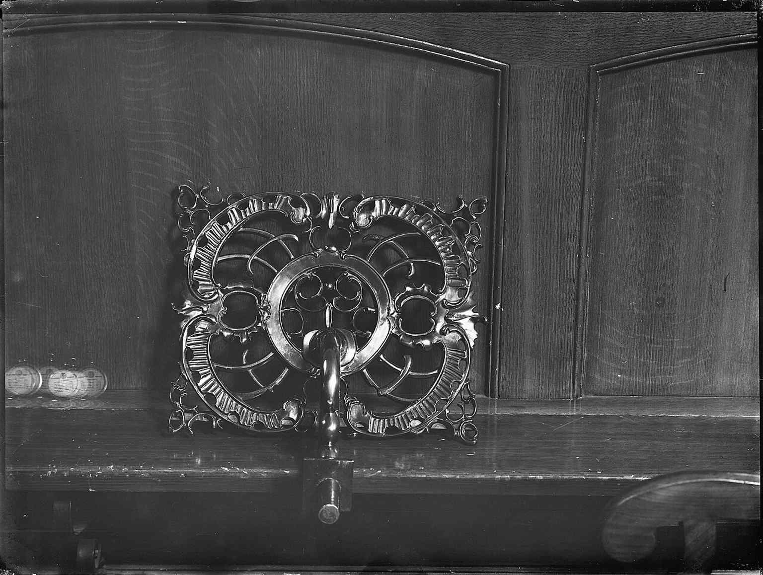 A close-up of the copper lectern at the baptismal fence (doophek), an example of the preserved 18th-century furniture within the church.
